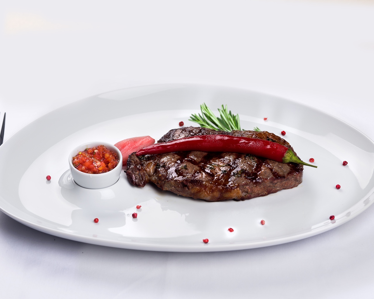 Стейк с кровью на тарелке с красным перцем