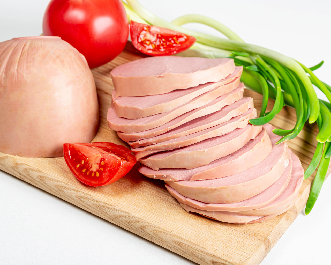 Вареная колбаса на доске с луком и помидором