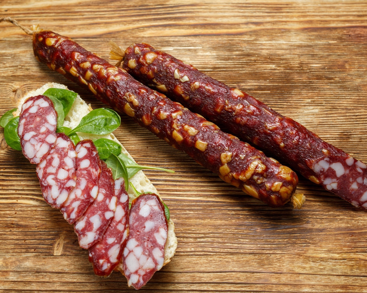 Вкусная сухая колбаса на столе с бутербродом