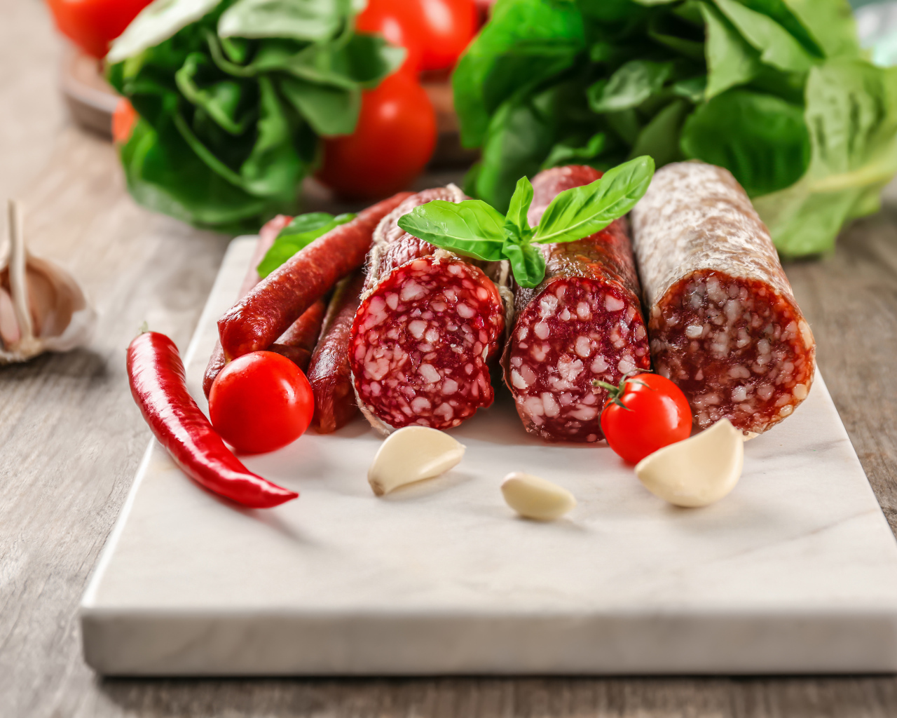 Вкусные колбасные изделия на столе с овощами