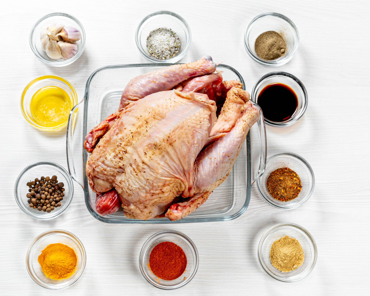 Свежая курица на противне на столе со специями 