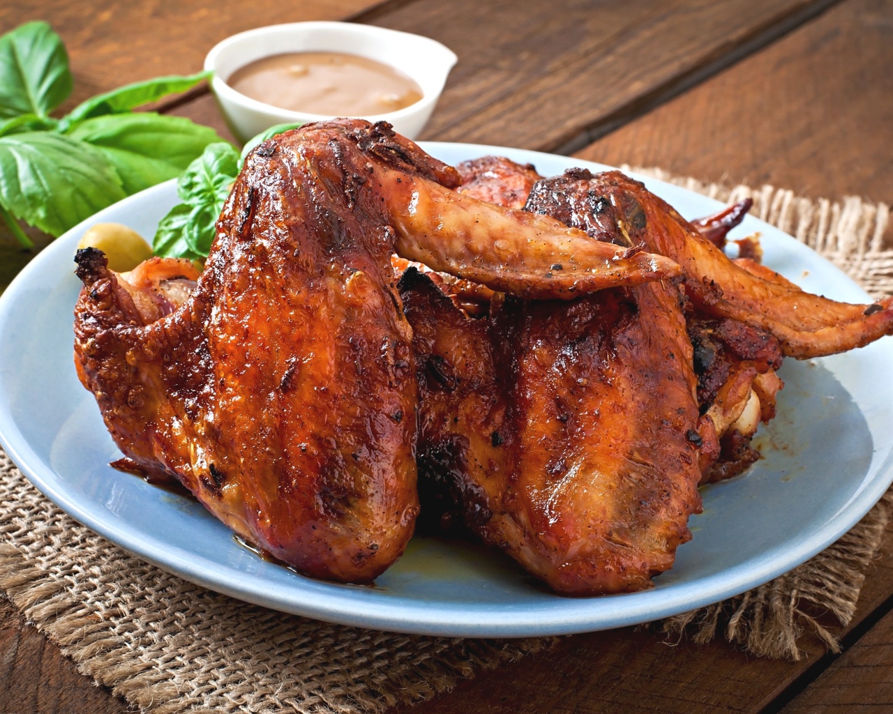Зажареные куриные крылышки на столе с соусом и базиликом