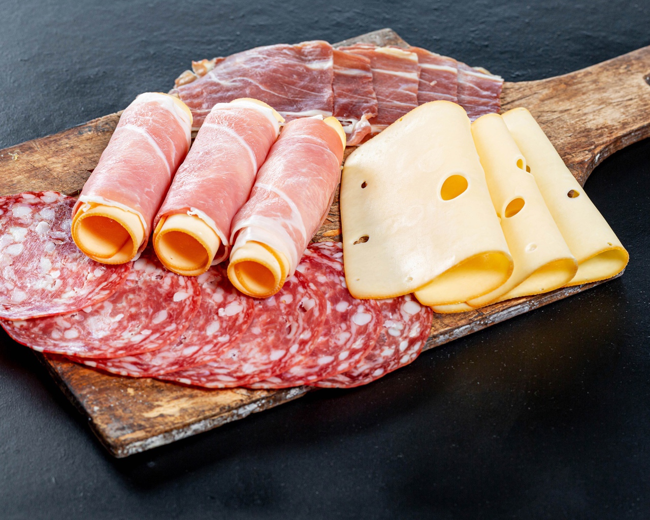 Рулеты из ветчины с сыром на столе с колбасой и мясом