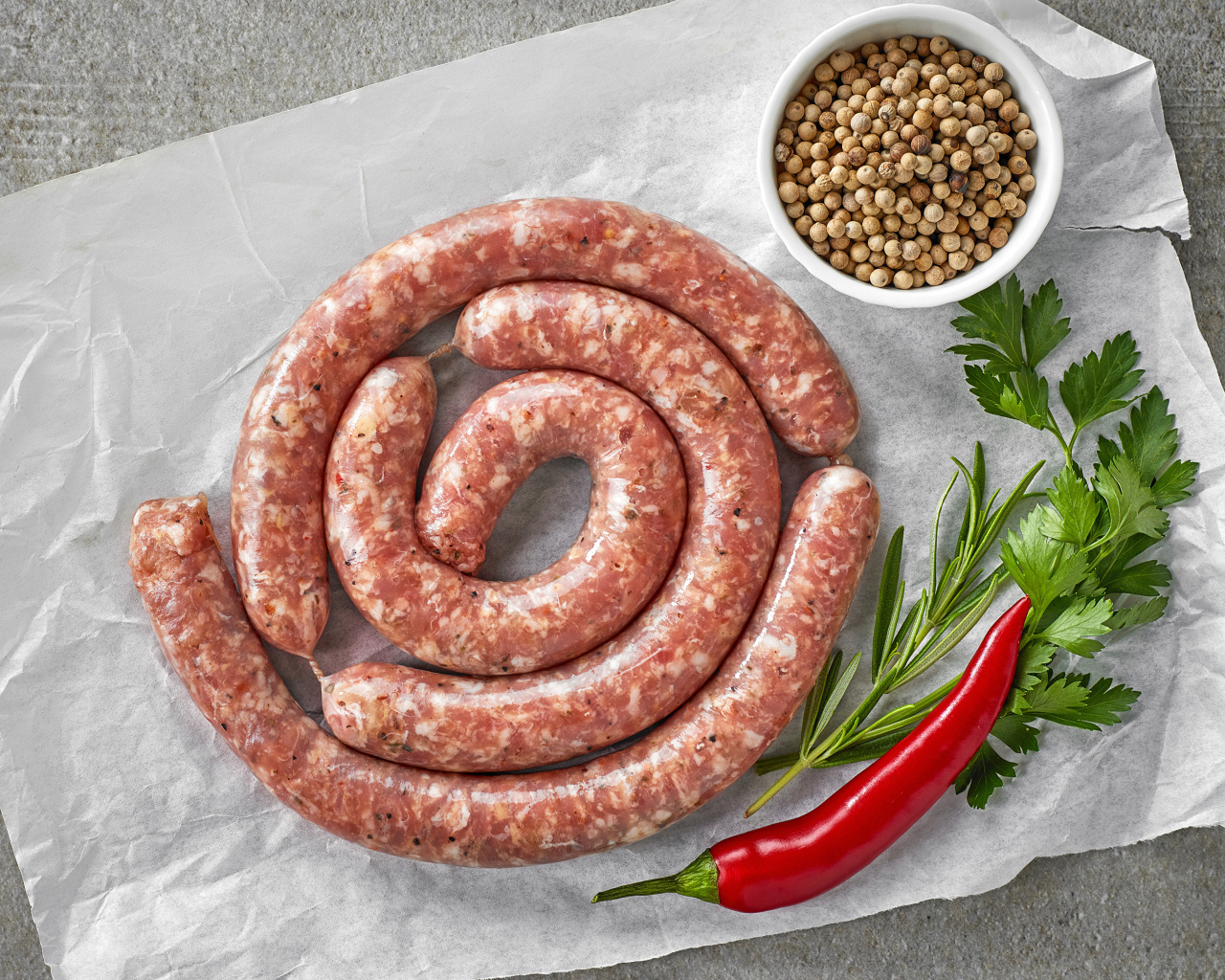 Домашняя колбаса на столе с зеленью и перцем