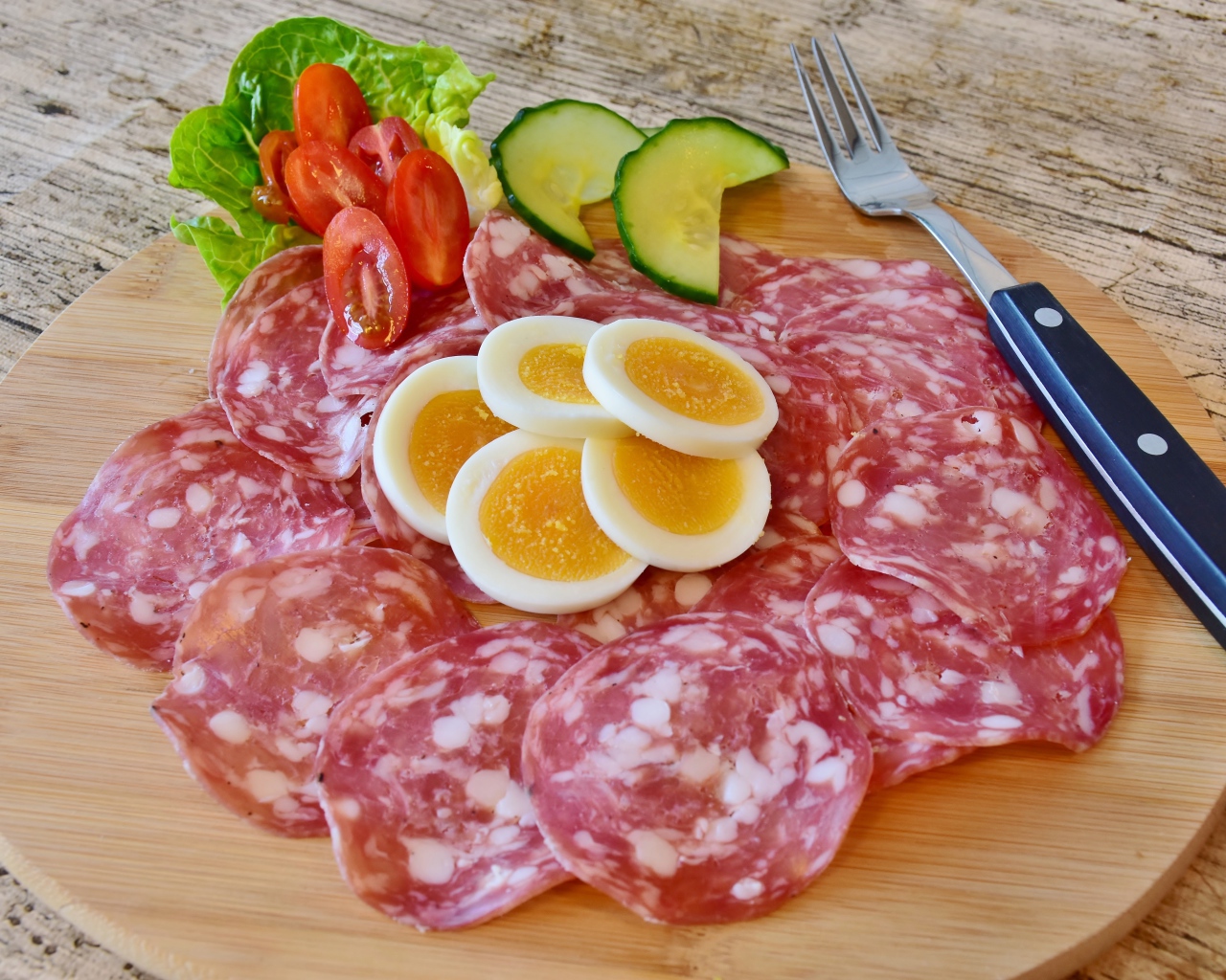 Колбаса салями на доске с яйцами и овощами