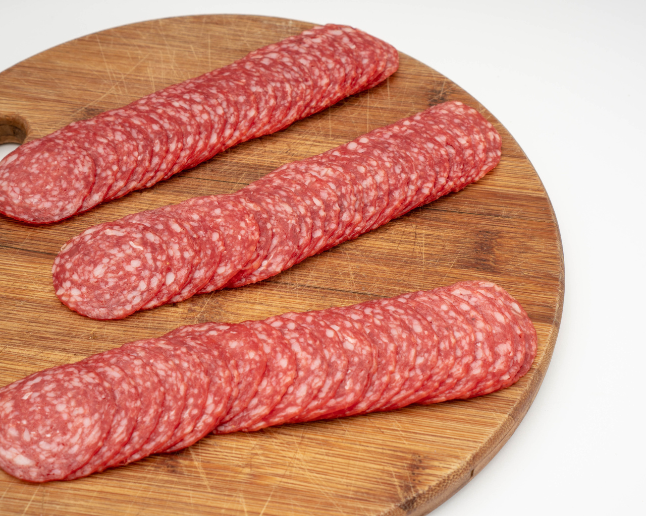 Колбаса тонко нарезана на разделочной доске 