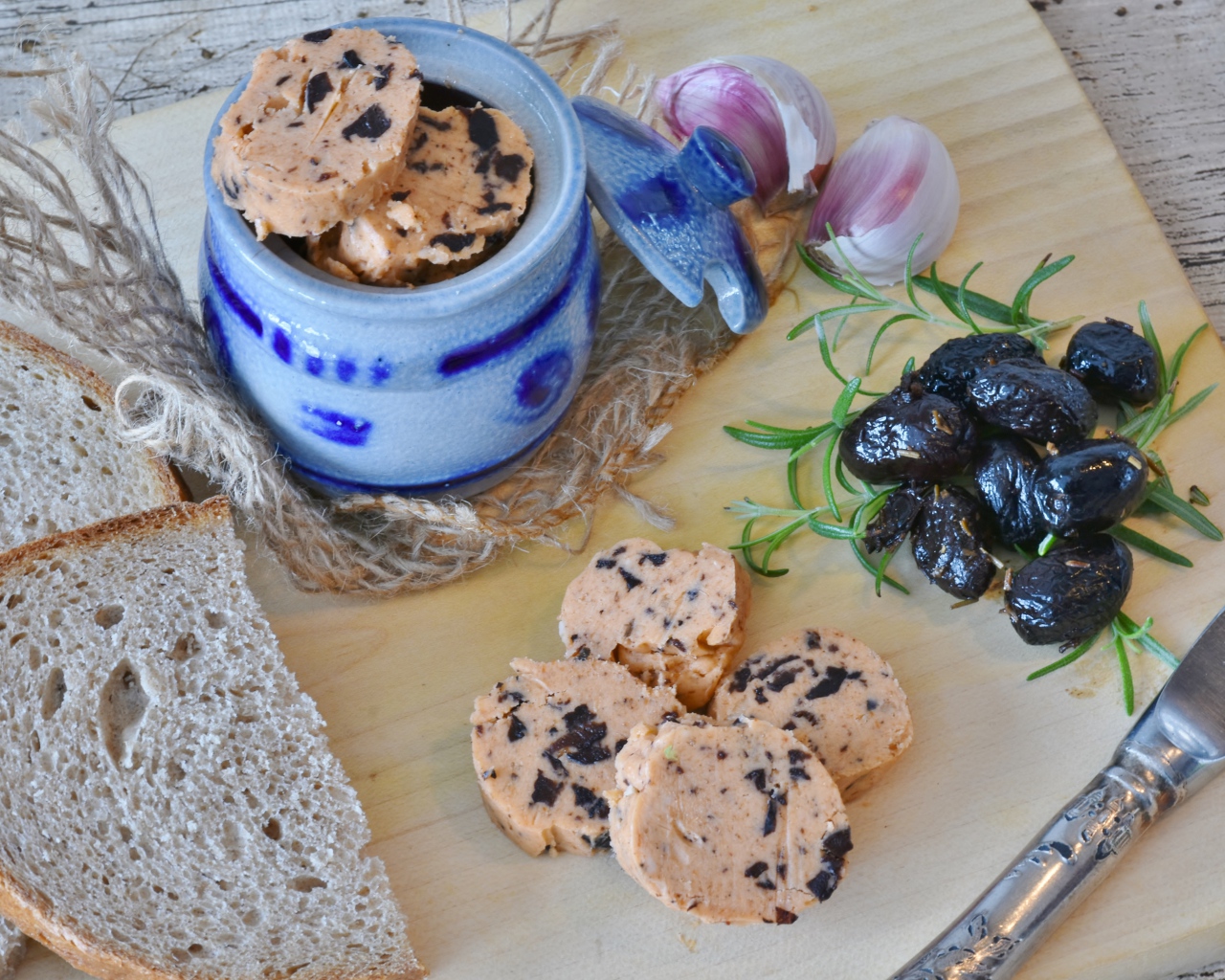 Колбаса с маслинами на столе с хлебом и чесноком