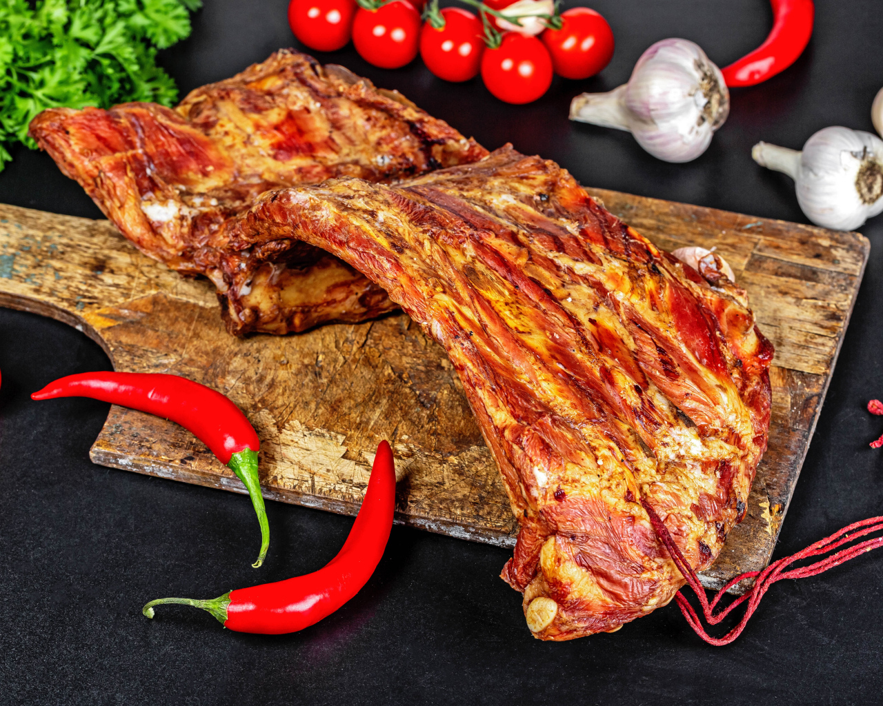 Копченые ребра на столе с красным перцем, чесноком и помидорами