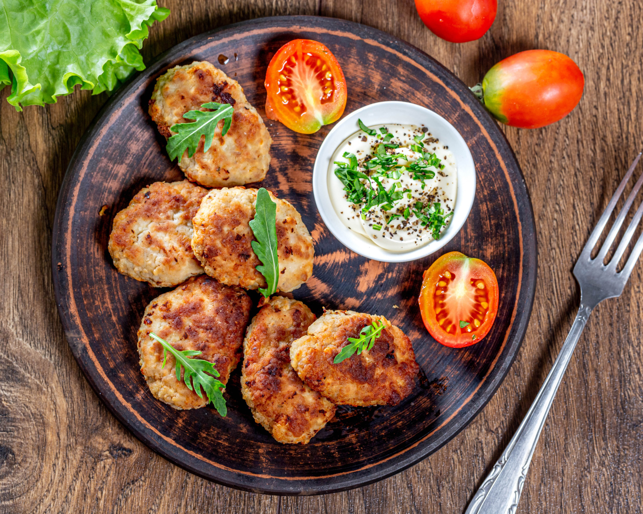 Вкусные котлеты на столе с соусом и помидорами