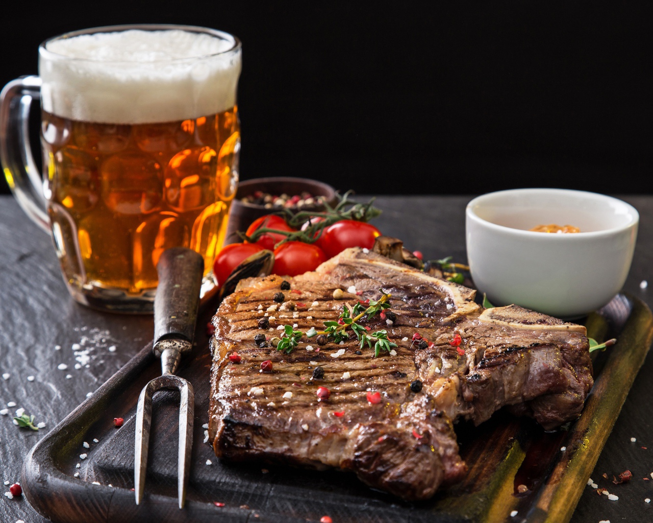 Вкусный кусок мяса на столе с помидорами и бокалом пива