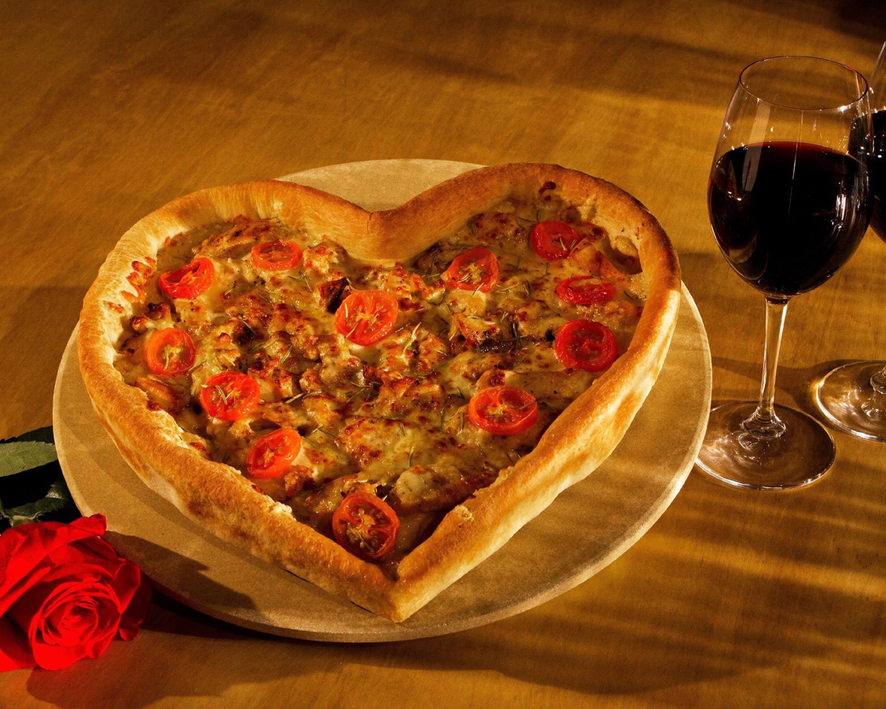 Пицца в форме сердца на столе с розой и двумя бокалами вина
