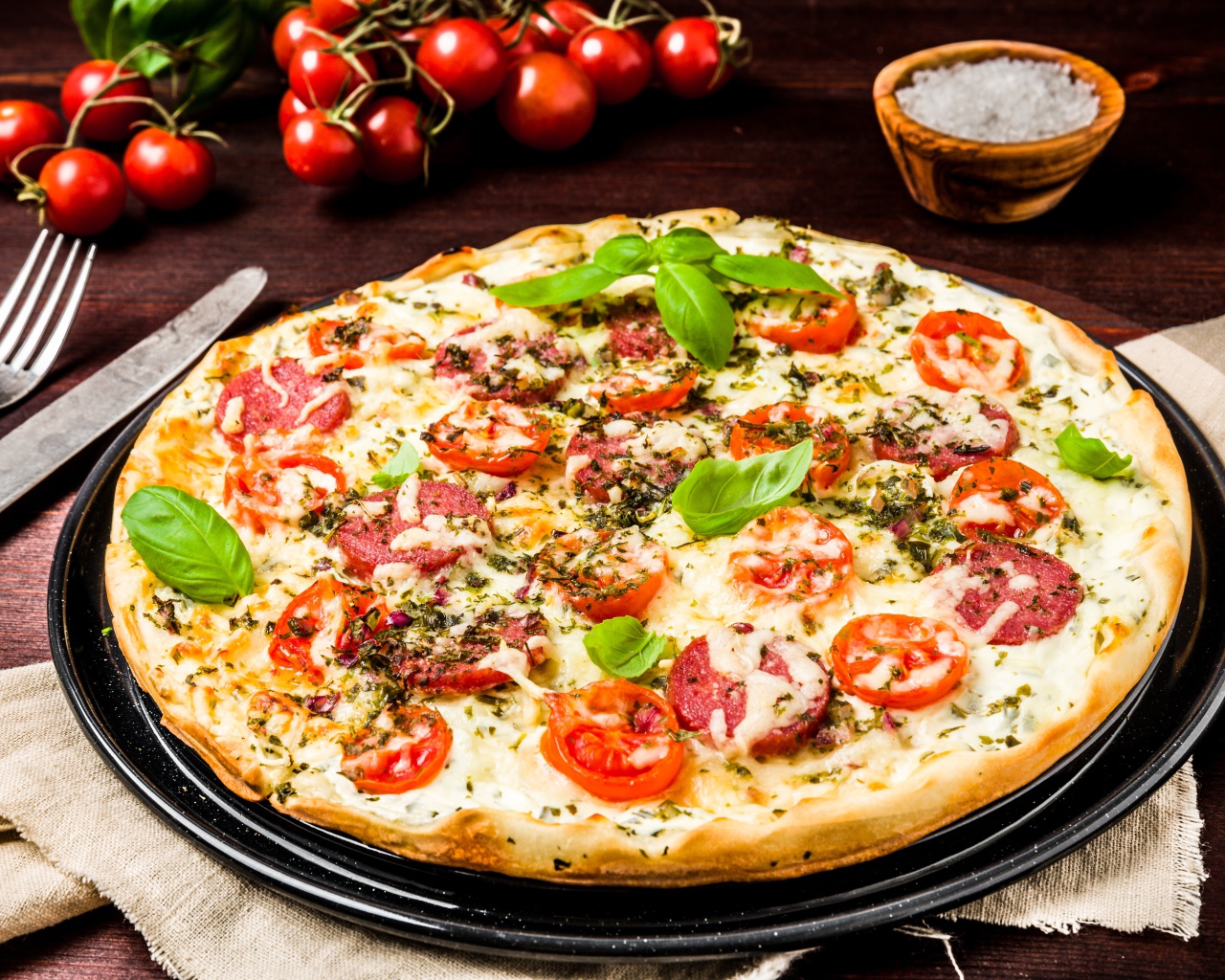Вкусная пицца с колбасой, сыром и помидорами на столе 