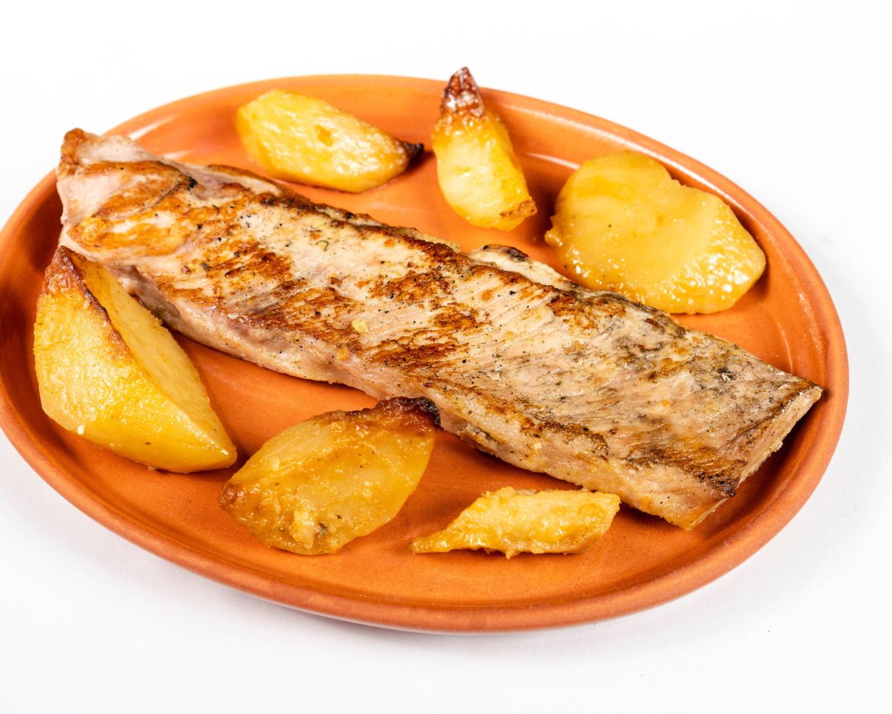 Кусок запеченной рыбы на тарелке с картофелем 
