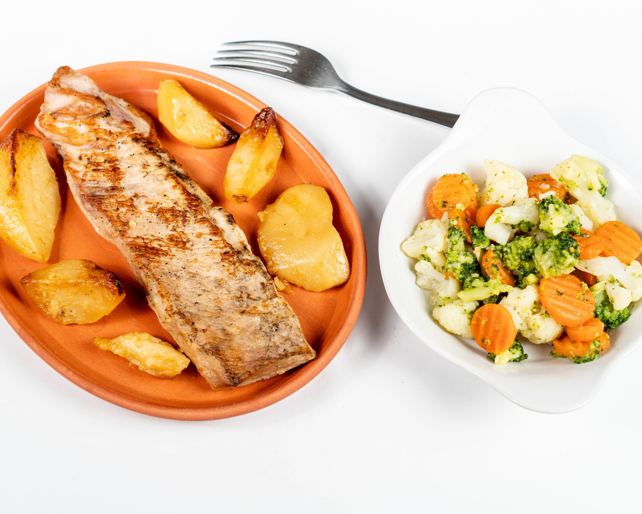 Кусок запеченной рыбы на тарелке с овощами 