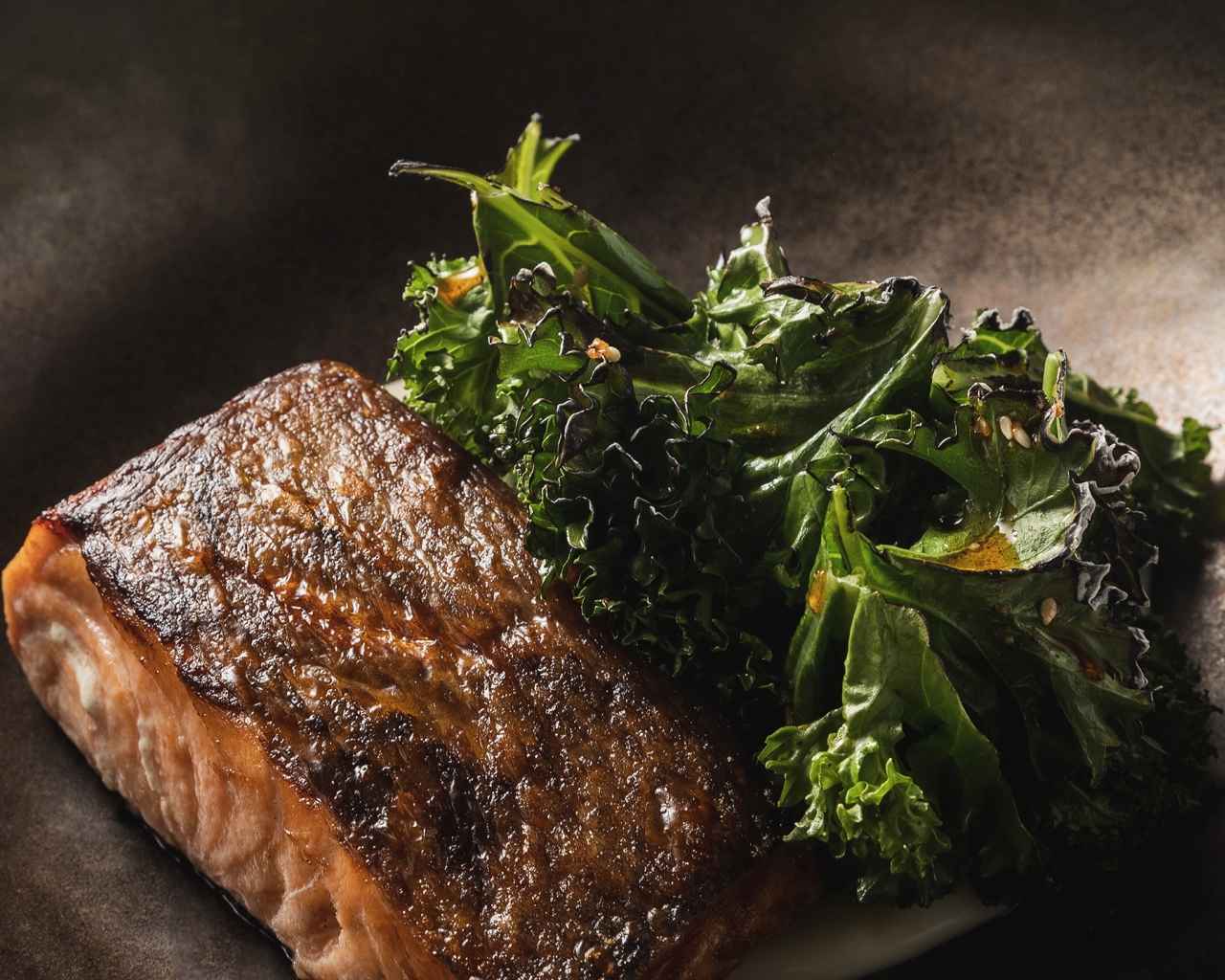 Кусок запеченной рыбы с листьями салата в сковороде 