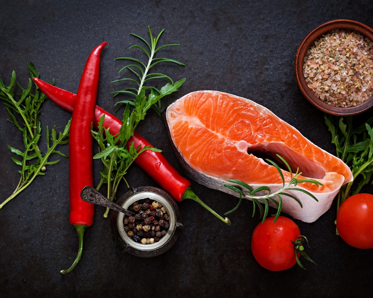 Кусок свежей красной рыбы на столе со специями, красным перцем и помидорами