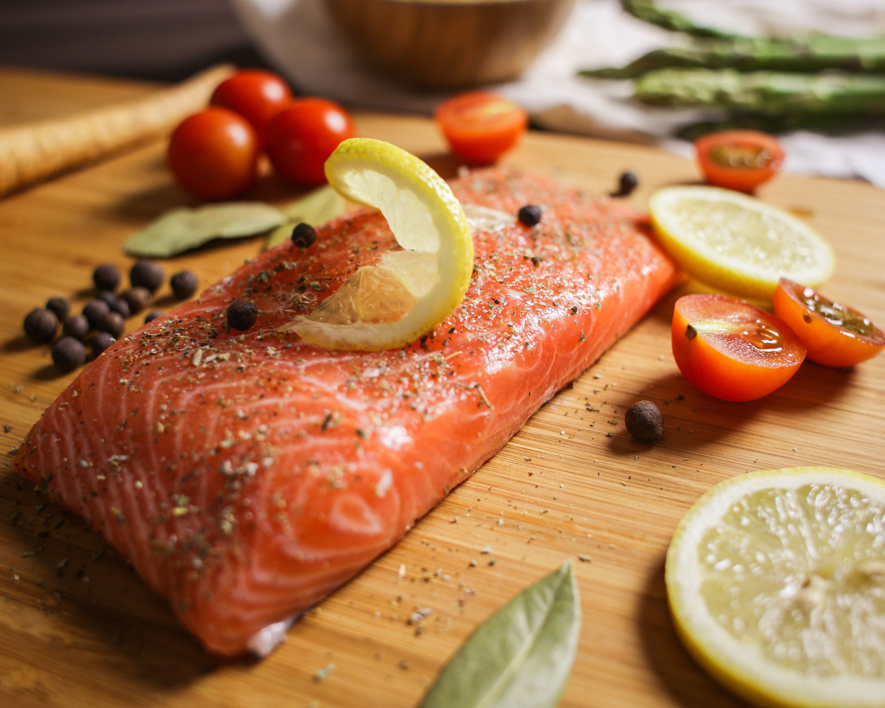 Кусок красной рыбы на доске с лимоном и помидорами