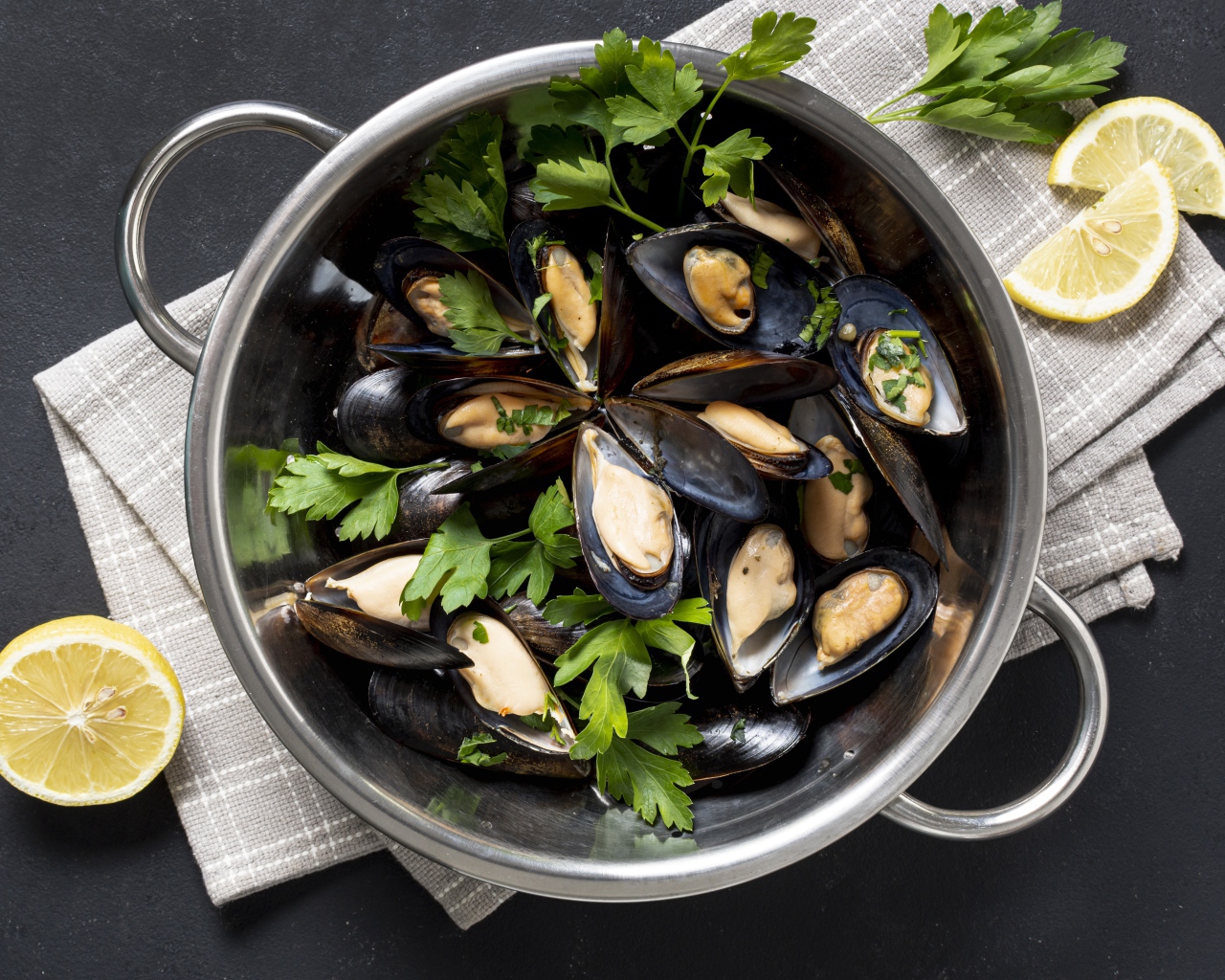 Свежие мидии в кастрюле с зеленью петрушки 