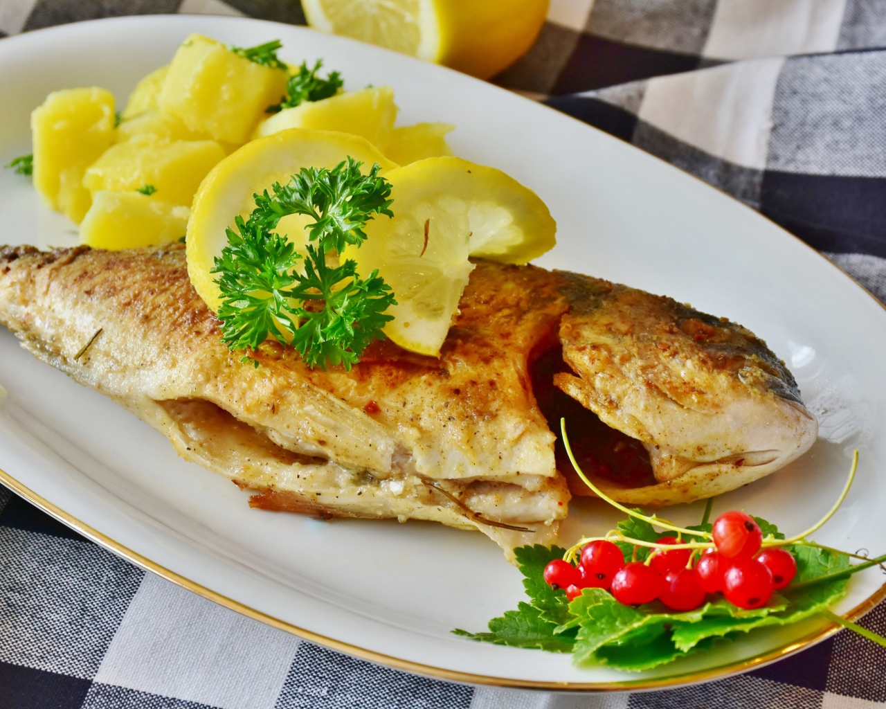 Жареная рыба с лимоном на тарелке с картофелем