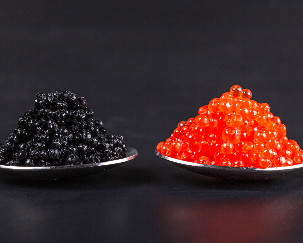 Красная и черная икра на ложках на сером фоне