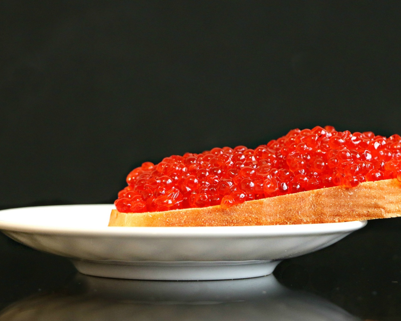 Бутерброд с красной икрой на белой тарелке 