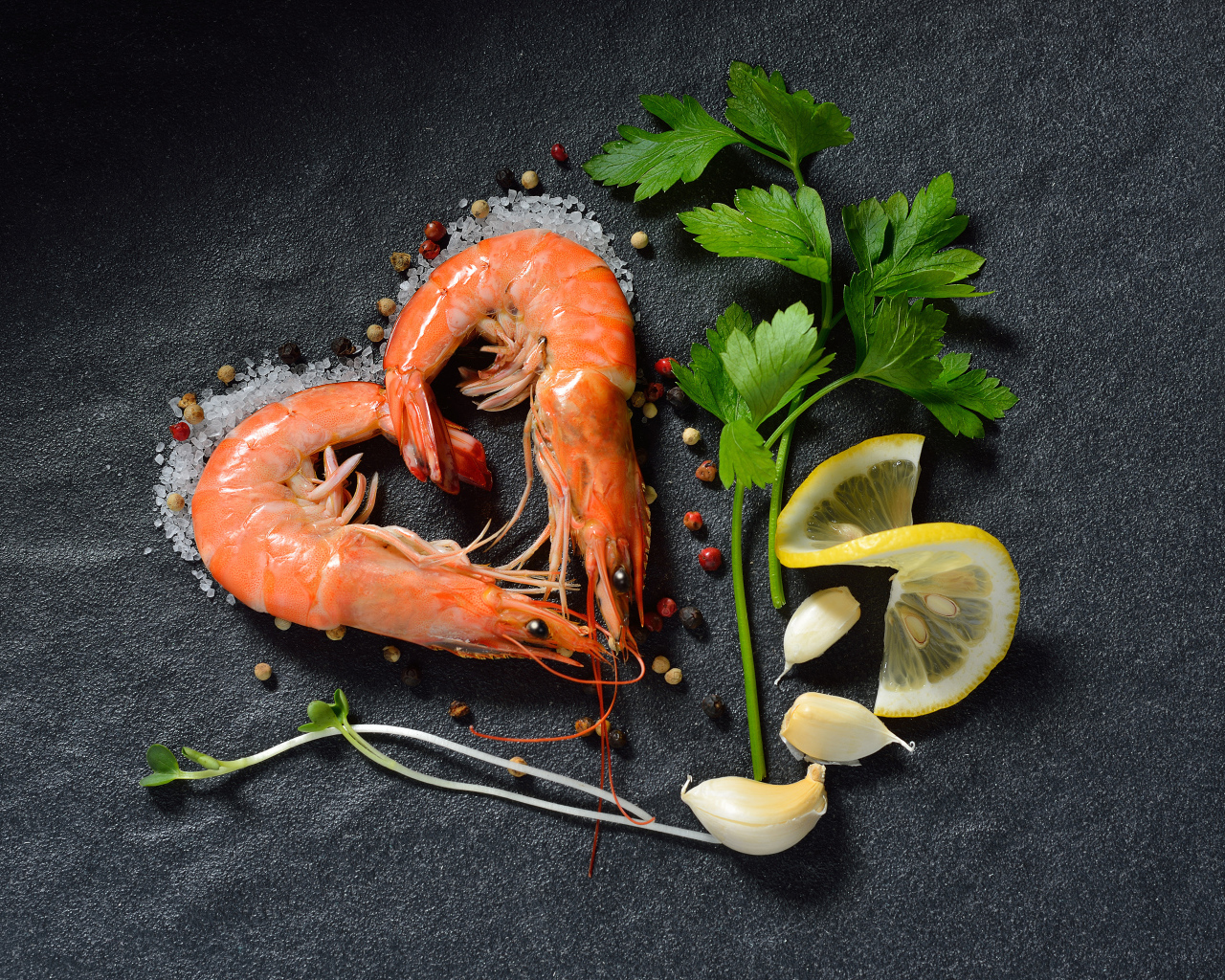 Сердце из креветок на сером столе с лимоном и веточкой петрушки 