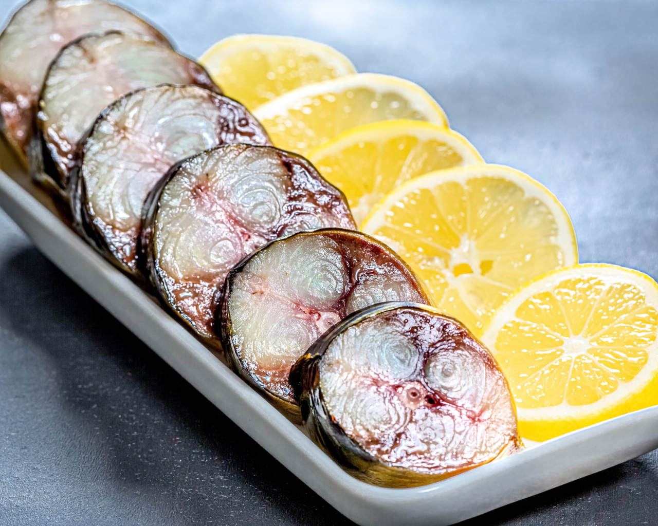 Sliced mackerel in a plate with slices of lemon