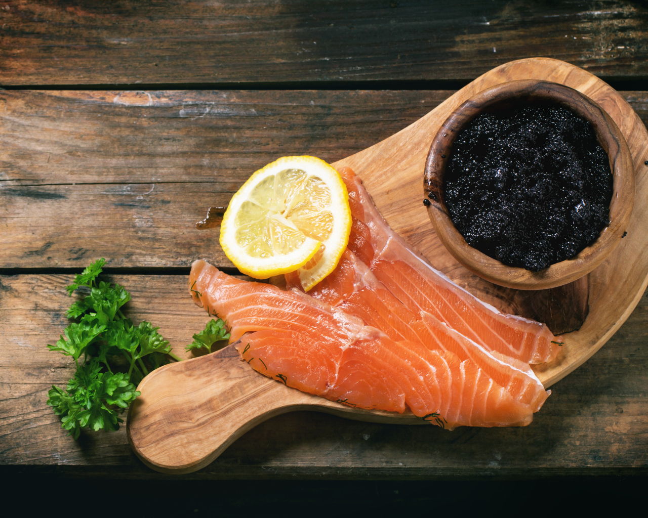 Кусочки красной рыбы с лимоном на столе с черной икрой 