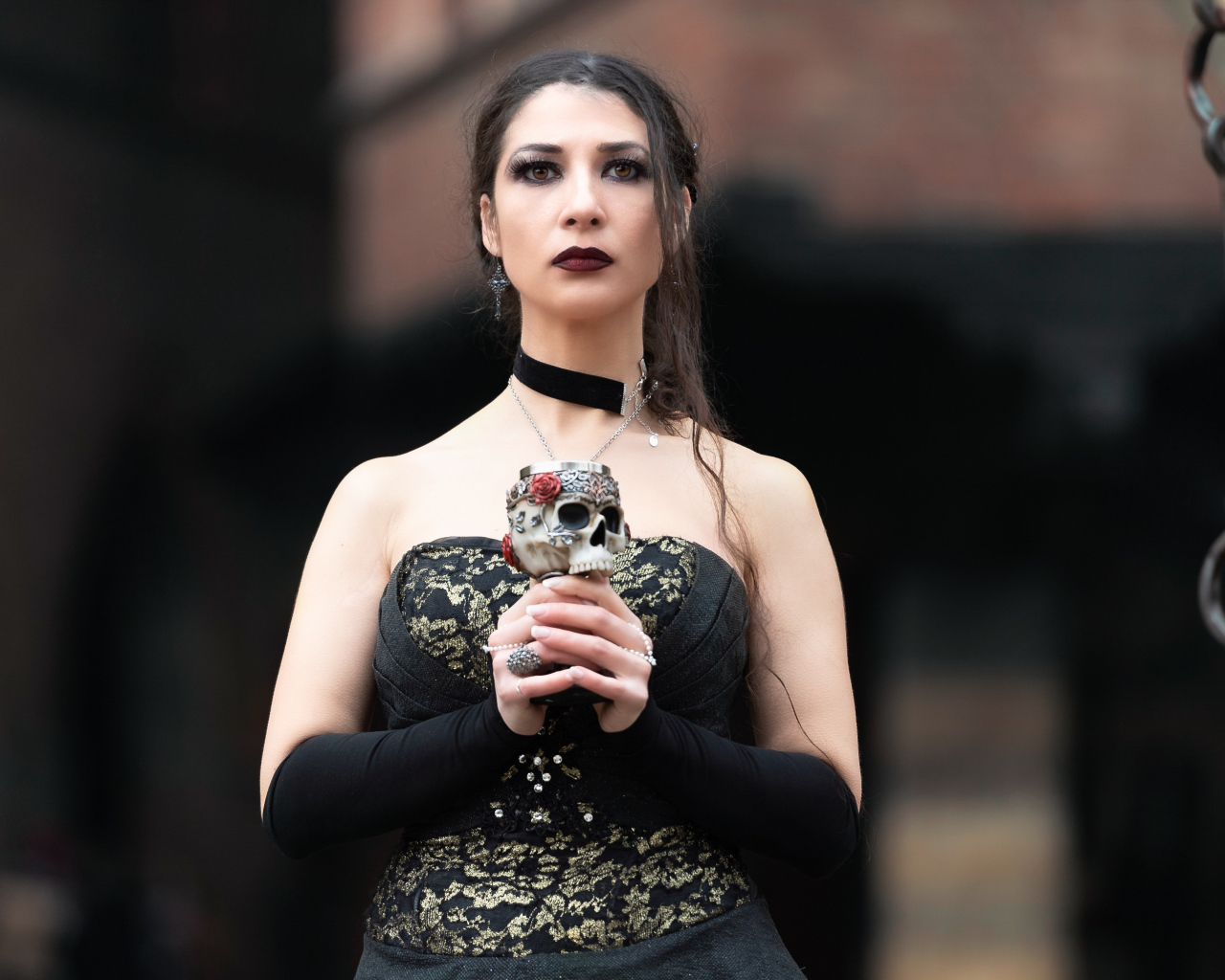 Девушка готка с бокалом - черепом в руках 