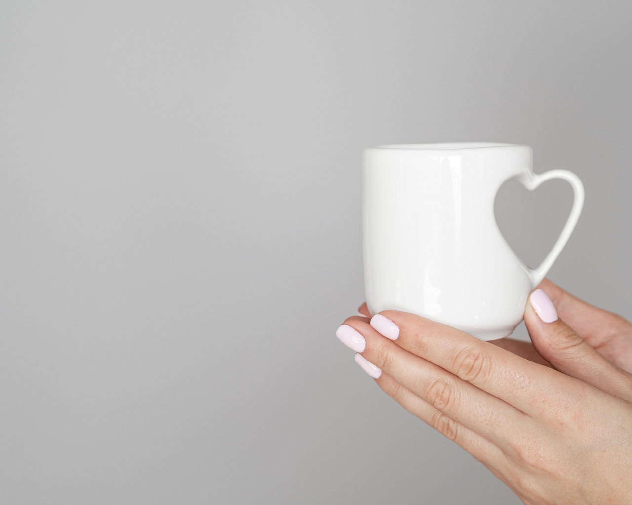 Белая кружка в руках девушки на сером фоне