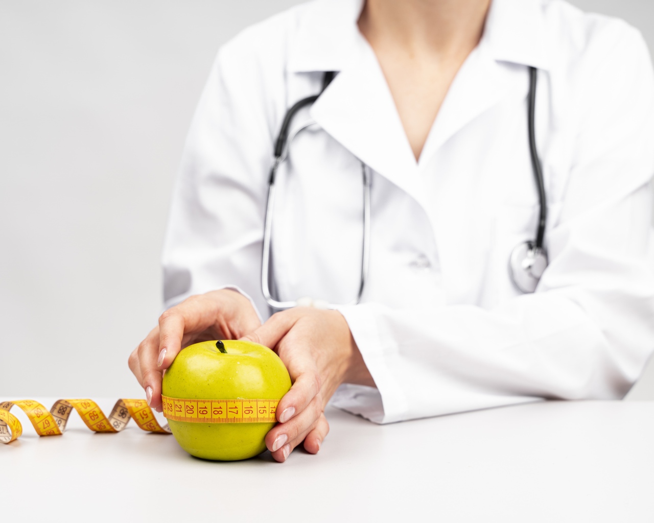 Женщина врач измеряет яблоко сантиметром 