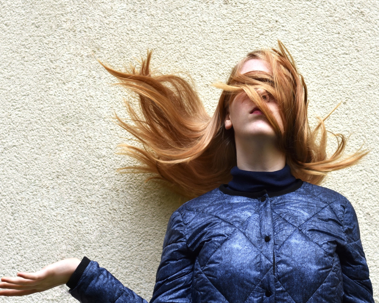 Девушка с волосами на лице стоит у стены