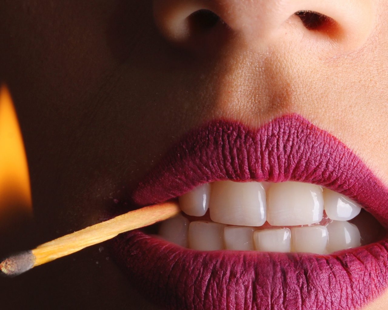Зажженная спичка в зубах у девушки 