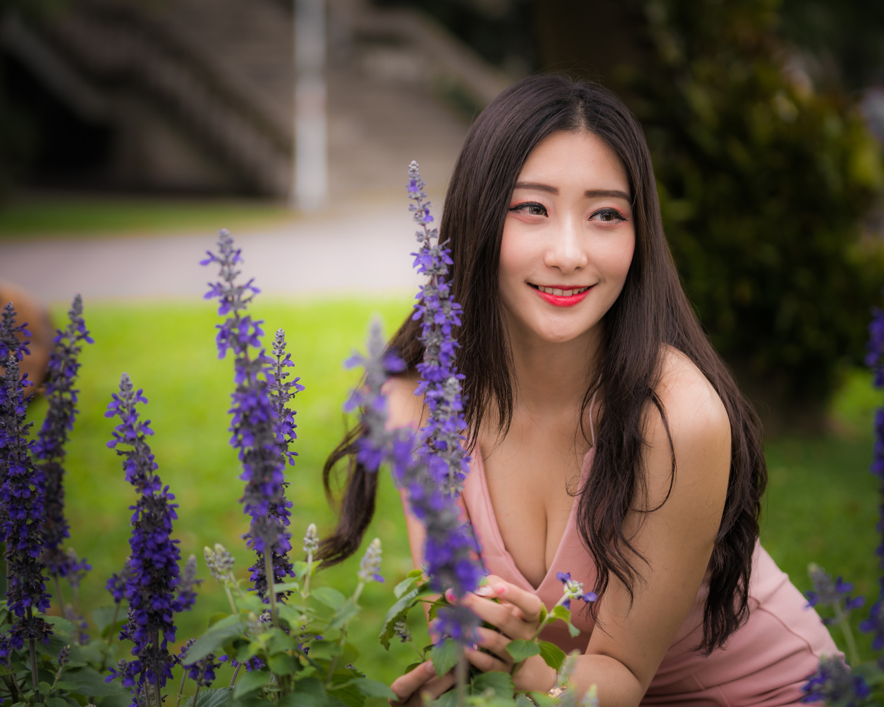 Улыбающаяся азиатка стоит у синих цветов 