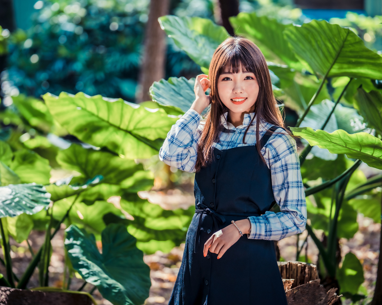 Улыбающаяся девушка азиатка в черном платье стоит в парке