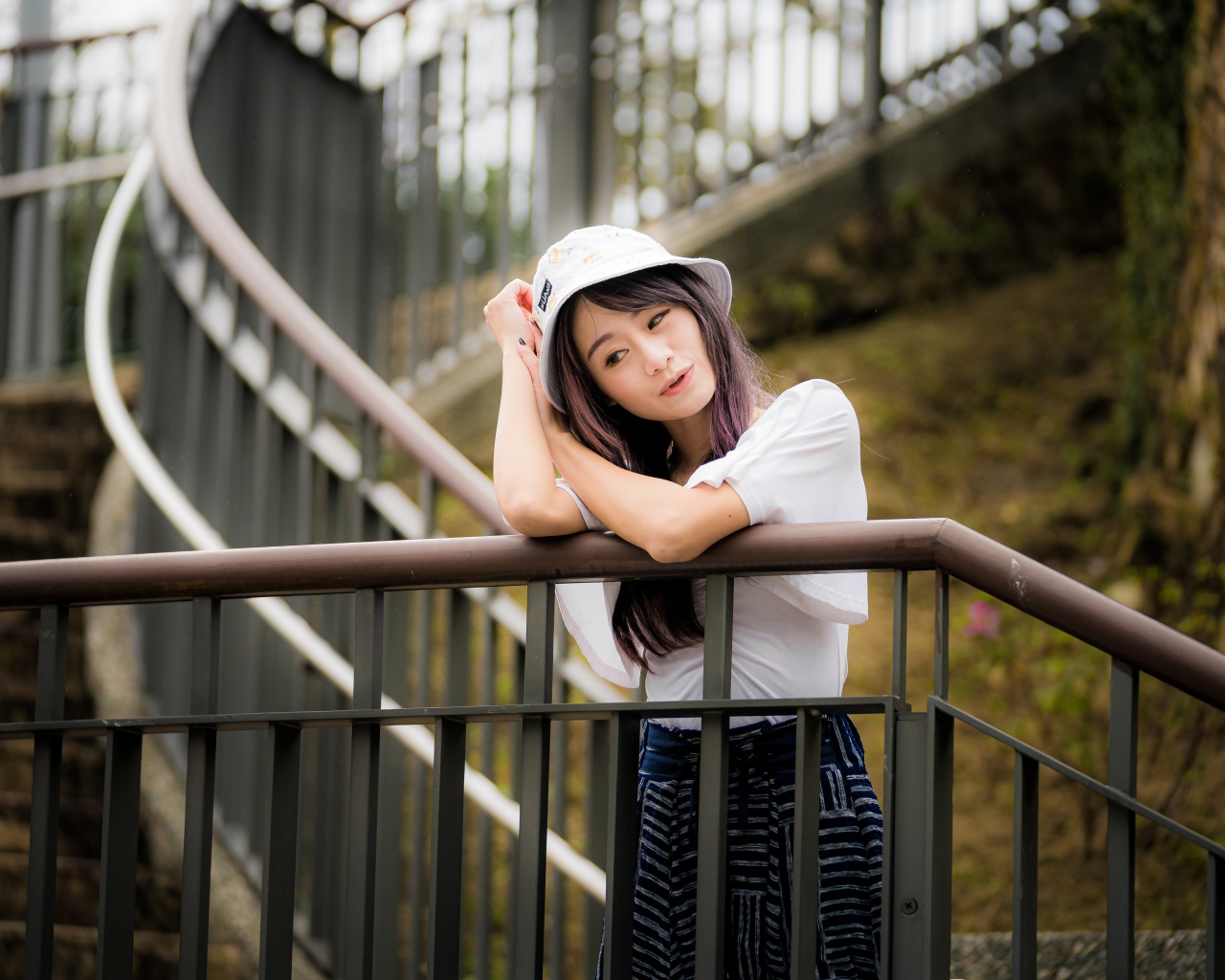 Молодая девушка азиатка стоит на лестнице у перил 