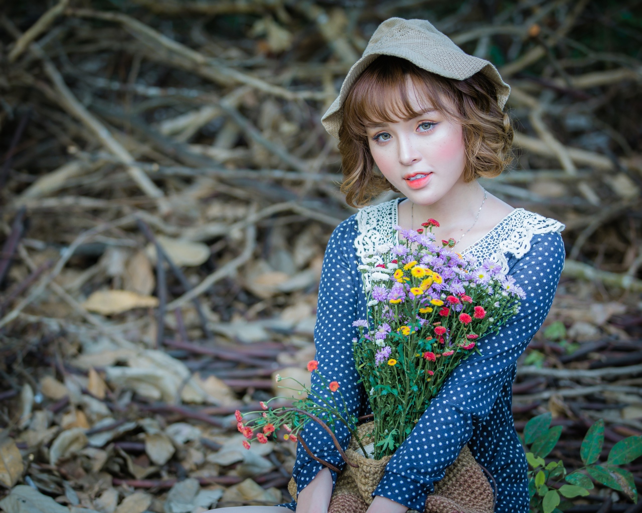 Молодая девушка азиатка с букетом цветов сидит на ветках