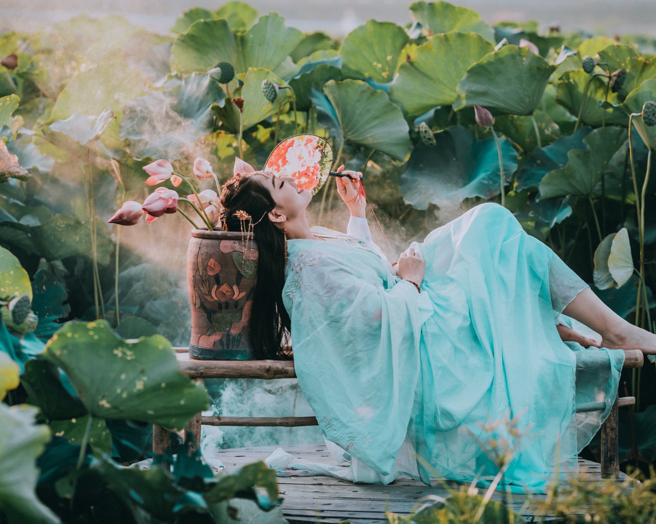 Девушка азиатка в красивом голубом платье на поле лотосов