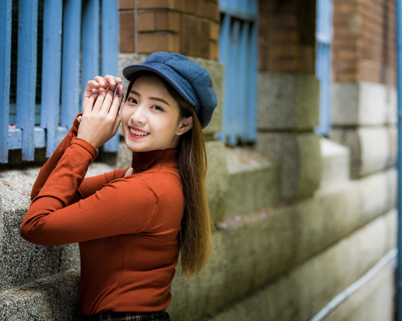 Девушка азиатка в кепке на стенке 