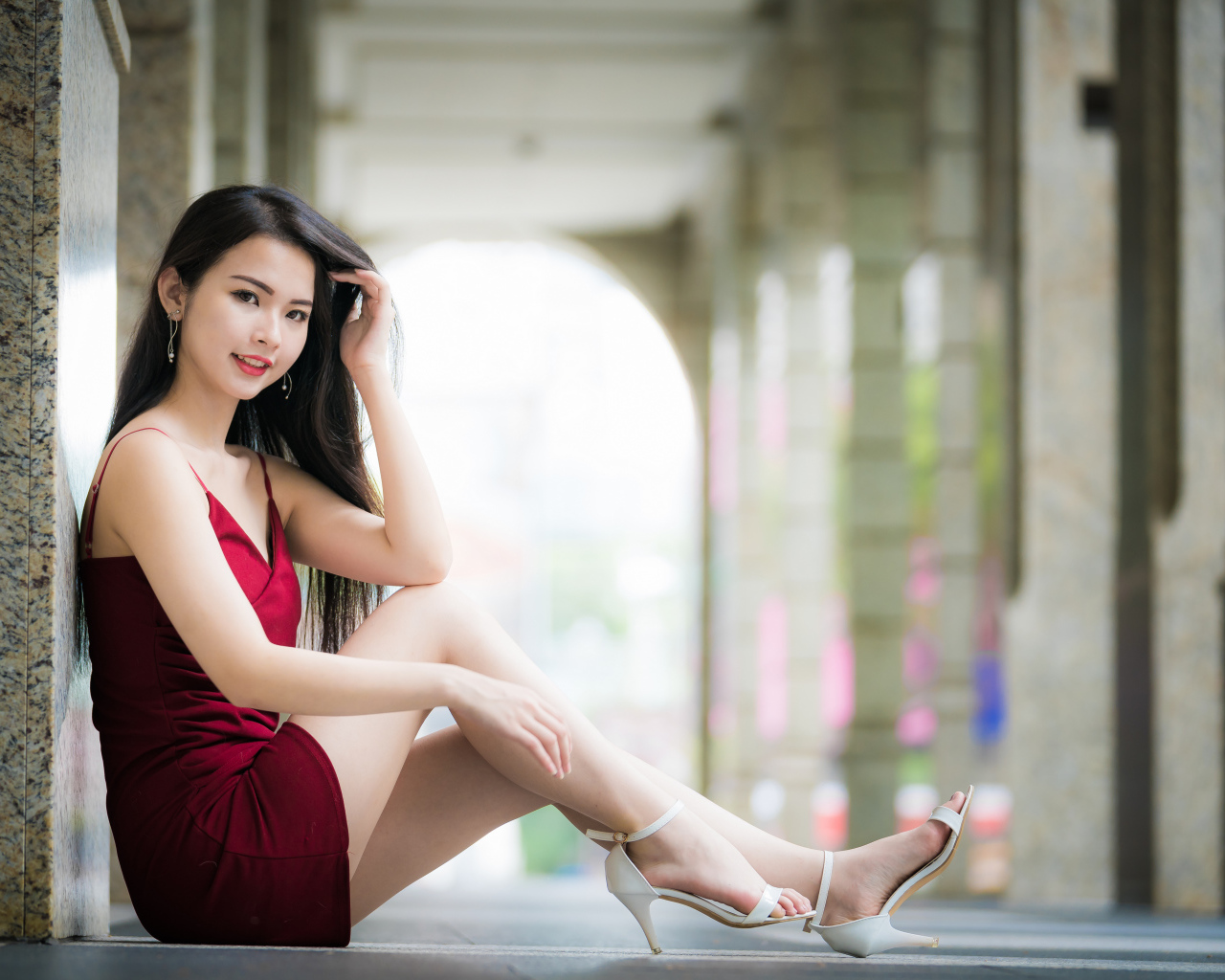 Девушка азиатка в красном платье сидит на полу