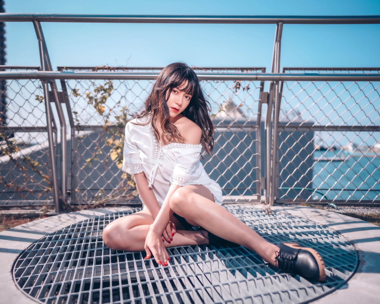 Девушка азиатка в белом наряде сидит на сетке