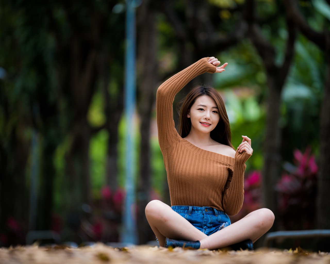 Девушка азиатка сидит в позе лотоса в парке 