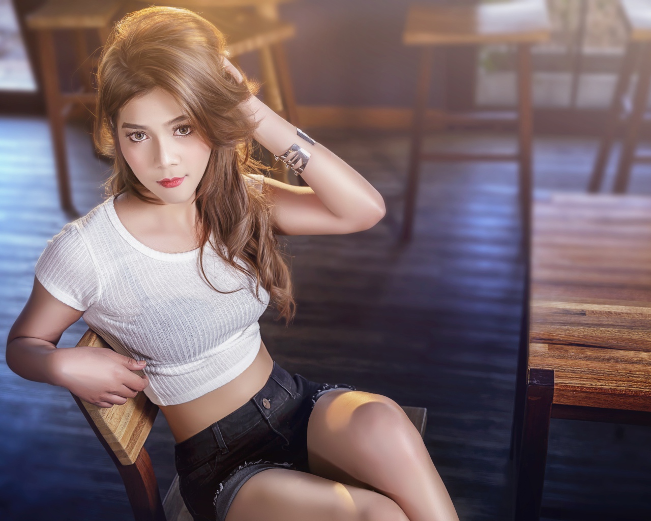 Девушка азиатка сидит на деревянном стуле в кафе