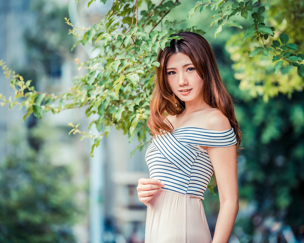 Девушка азиатка стоит под деревом в парке 