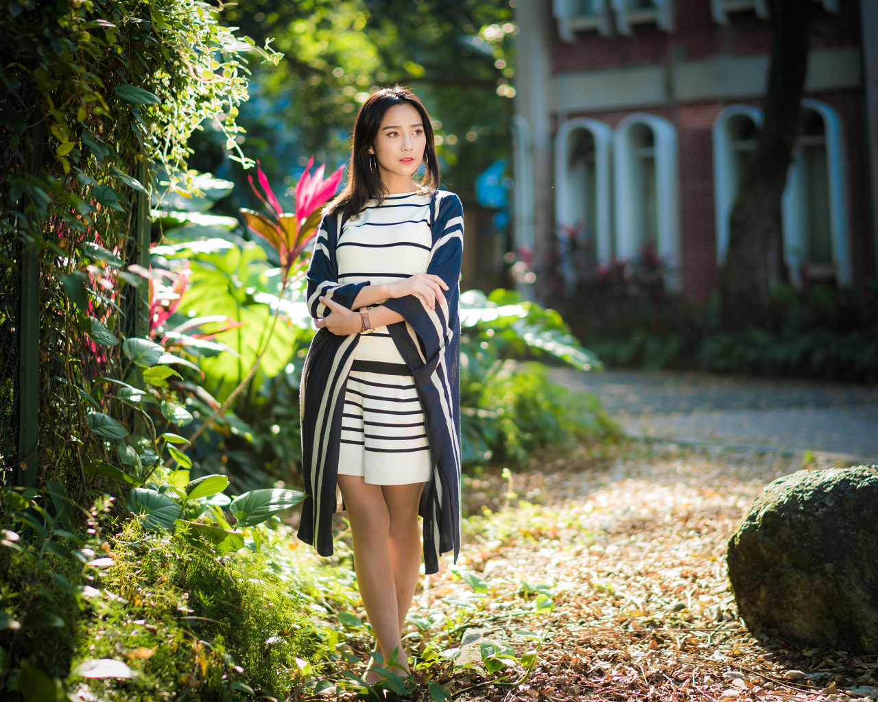 Девушка азиатка идет по улице у забора