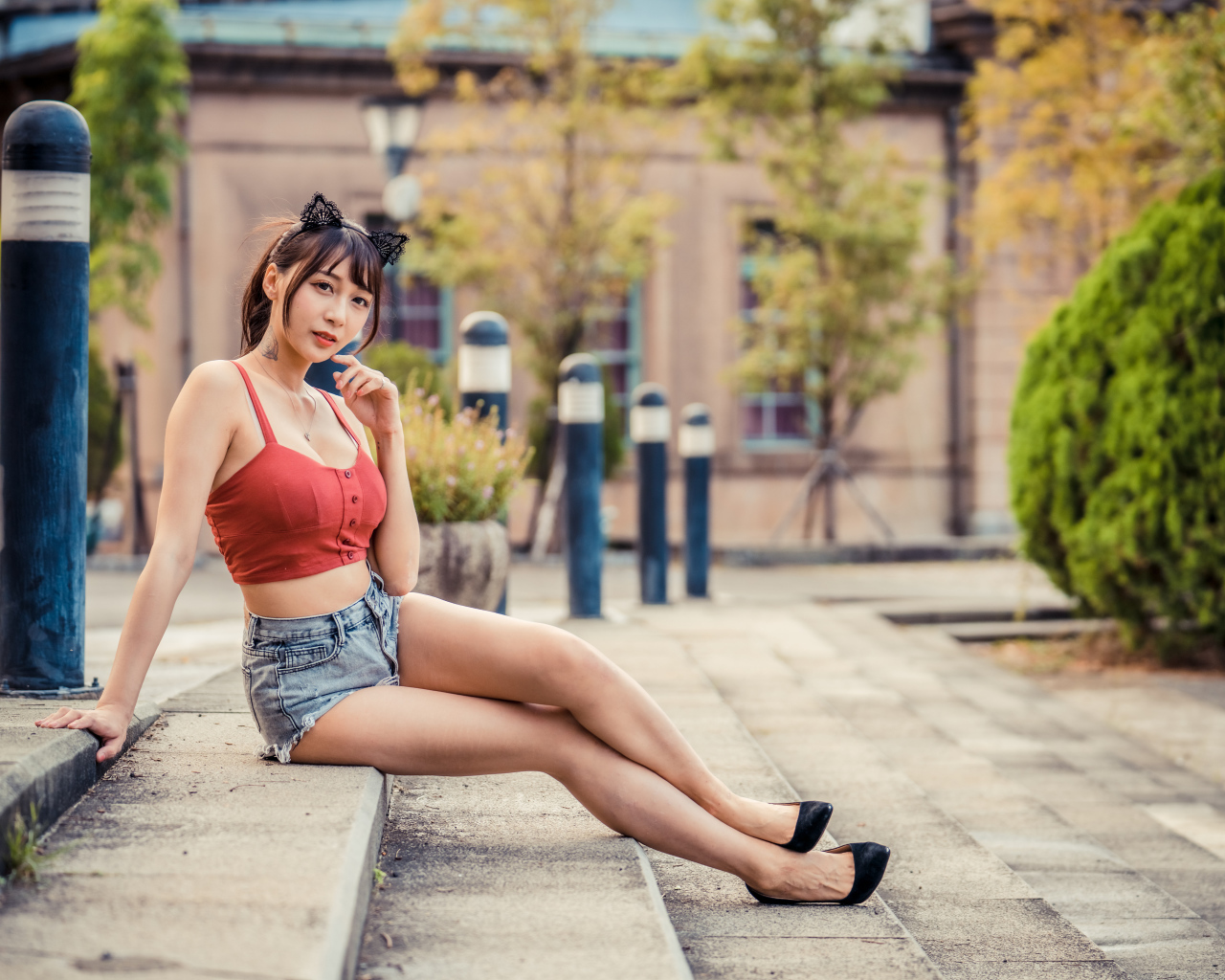 Азиатка в шортах сидит на ступенях 