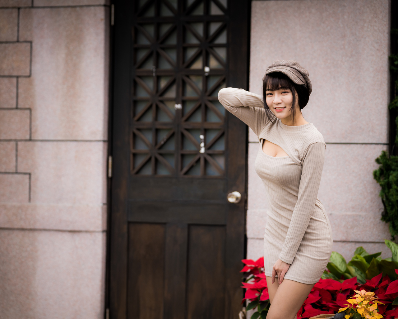 Красивая азиатка в платье стоит у двери 