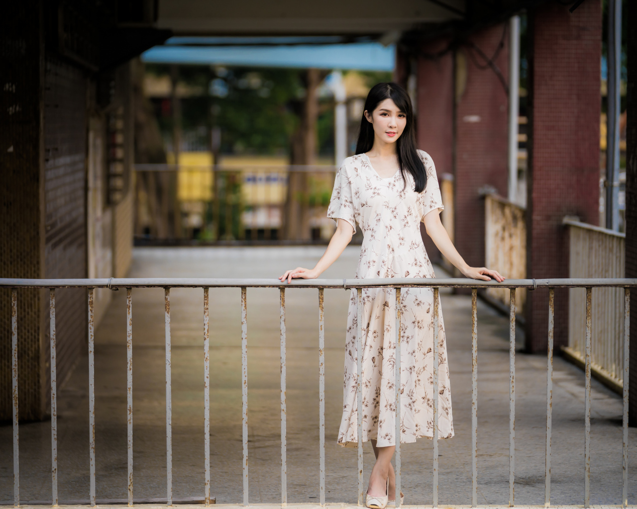 Красивая азиатка в платье стоит у перил
