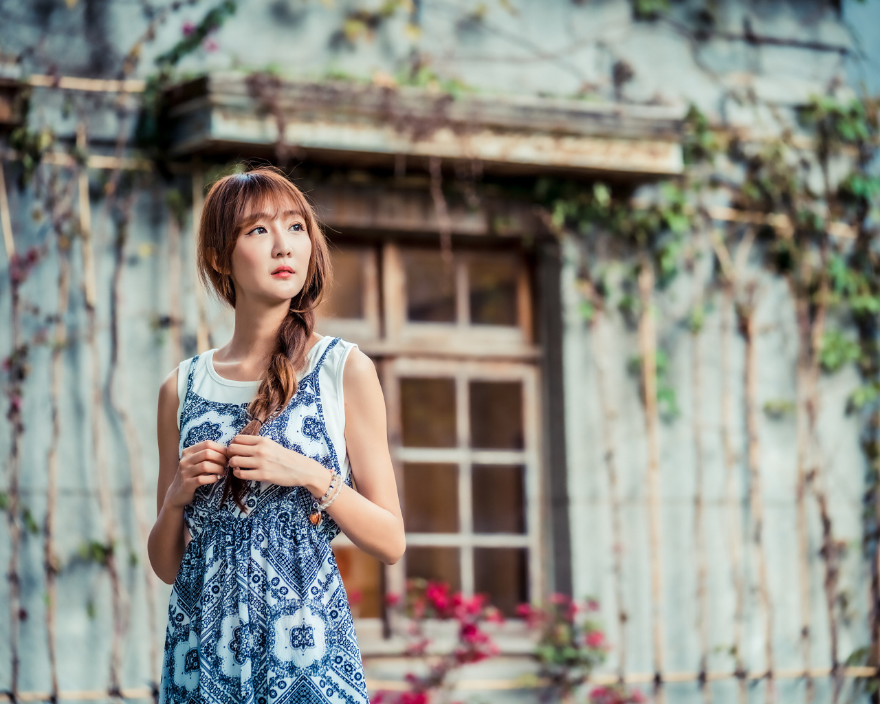Красивая девушка азиатка в сарафане у старого дома 