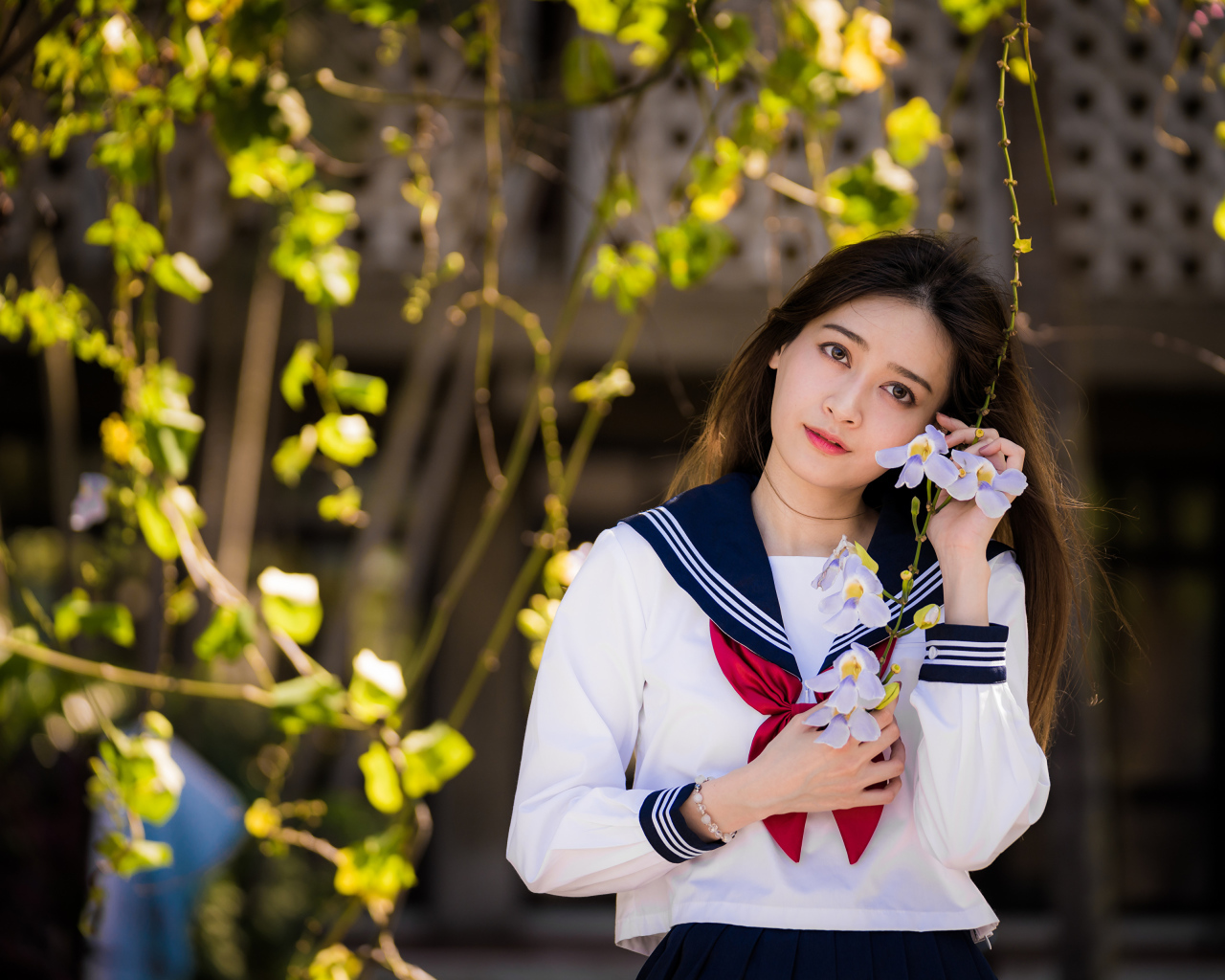 Красивая девушка азиатка в форме с цветами в руках 